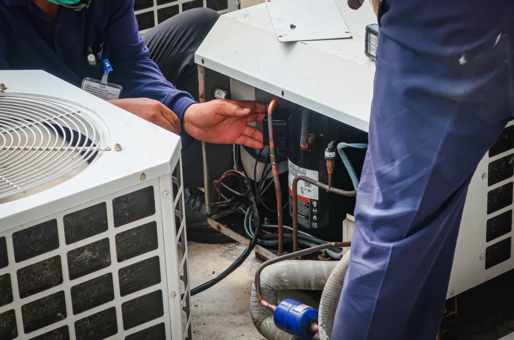 Two men repairing an AC unit